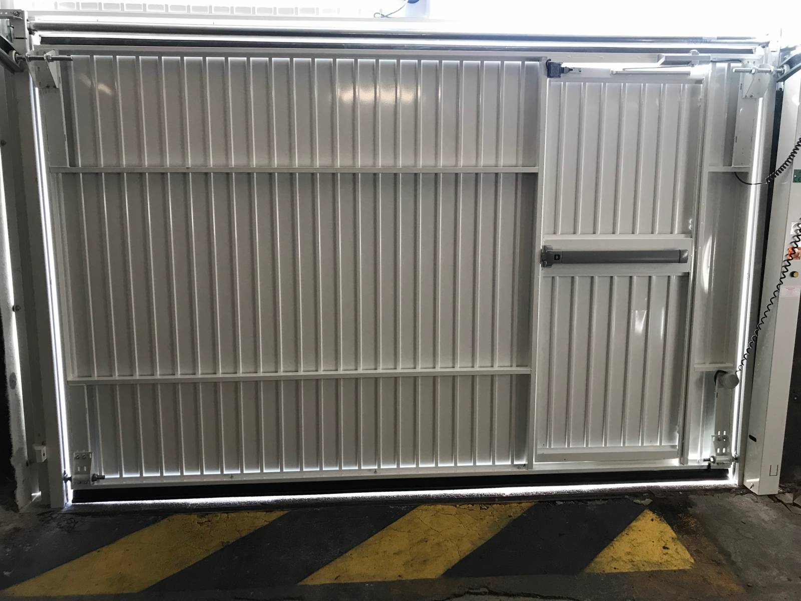 Porte basculante motorisée Doitrand avec portillon intégré à usage intensif et collectif près de Marseille